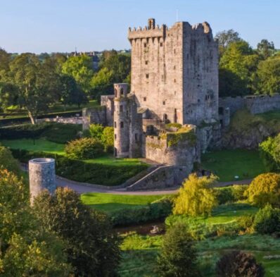 Scenic view of historic stone castle surrounded by lush green gardens, offering a tranquil and unique guest experience.