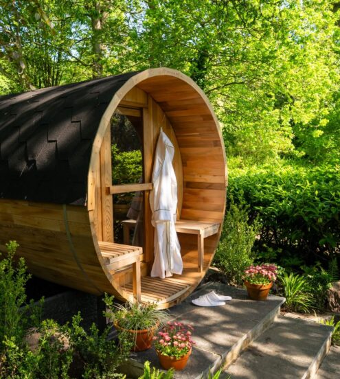 Cosy outdoor sauna with robes amidst lush garden at tranquil hotel retreat.