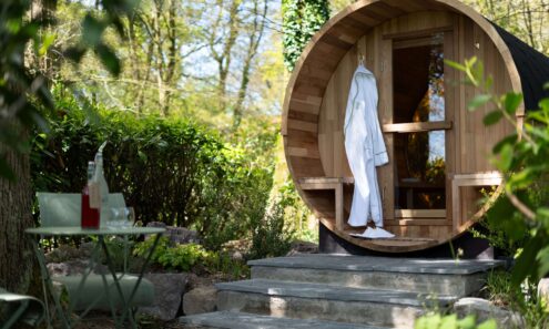 Cozy garden sauna with robe, surrounded by lush greenery and outdoor seating, perfect for a relaxing hotel stay.