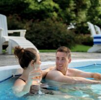 Couple relaxing in sparkling outdoor pool with lush garden views, enjoying serene ambience at luxury British hotel.