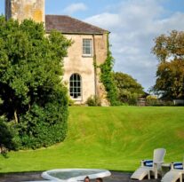 Guests enjoying a relaxing swim in the outdoor pool, with historic castle-like building and lush gardens in the background.