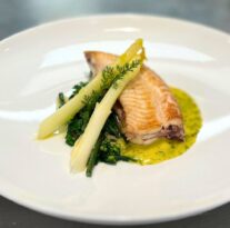 Elegant seafood dish with asparagus, served on a white plate with vibrant sauce, highlighting fine dining experience.