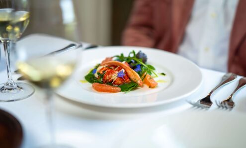 Elegant hotel dining with gourmet lobster salad, fresh greens, and fine wine set on a crisp white tablecloth.