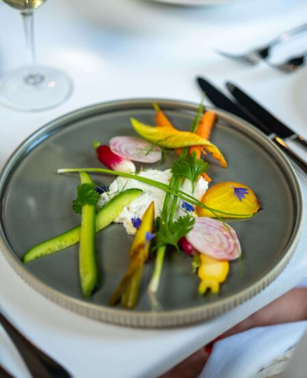 Elegant gourmet dish with colourful vegetables on fine dining table, enhancing luxury hotel experience.