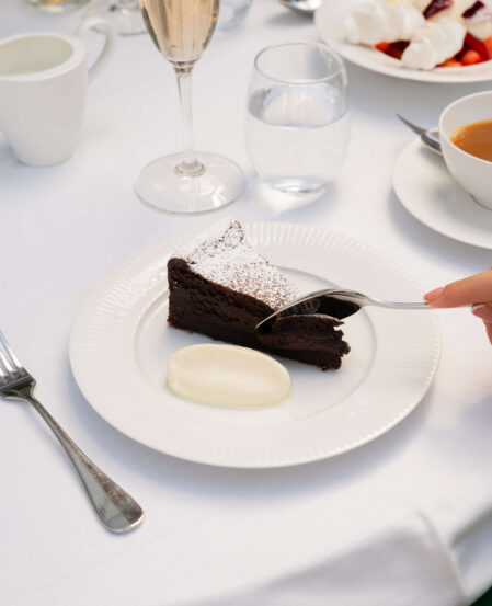 Luxurious hotel dining with decadent chocolate cake, fresh fruit, and sparkling wine in an elegant setting.