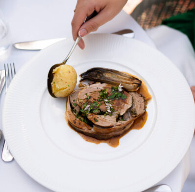 Savoury lamb dish with herbs, potatoes, and chicory on a white plate, showcasing dining elegance at our luxury hotel restaurant.