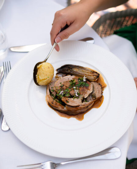 Savoury lamb dish with herbs, potatoes, and chicory on a white plate, showcasing dining elegance at our luxury hotel restaurant.