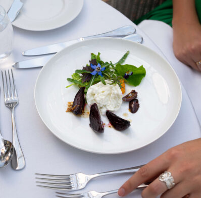 Elegant dining with gourmet salad on white tablecloth at luxury hotel restaurant, showcasing fine dining experience.