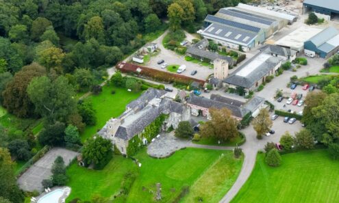 Aerial view of charming countryside hotel with lush gardens, outdoor pool, and historic architecture ideal for relaxation.