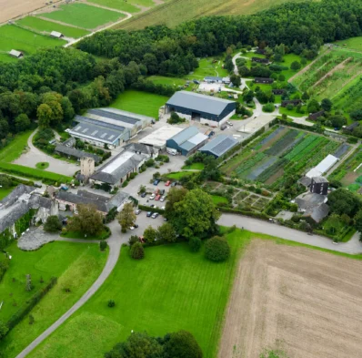 Aerial view of countryside hotel with lush gardens, historic buildings, and serene landscape, ideal for a relaxing getaway.